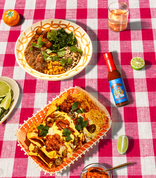 Iku's Burrito and Nachos on a table with a bottle of Mat's Hot Shop Spiceland Taco Sauce