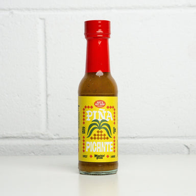 Bottle of Pina Picante sauce with a red cap on a white background