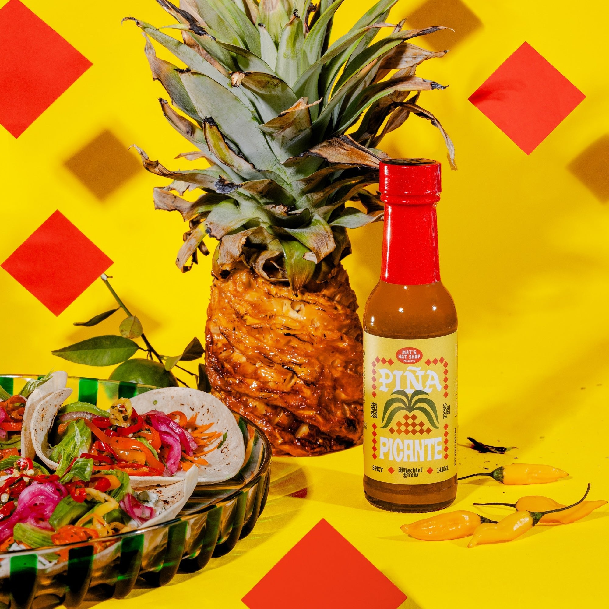 Pineapple with a bottle of hot sauce on a yellow background